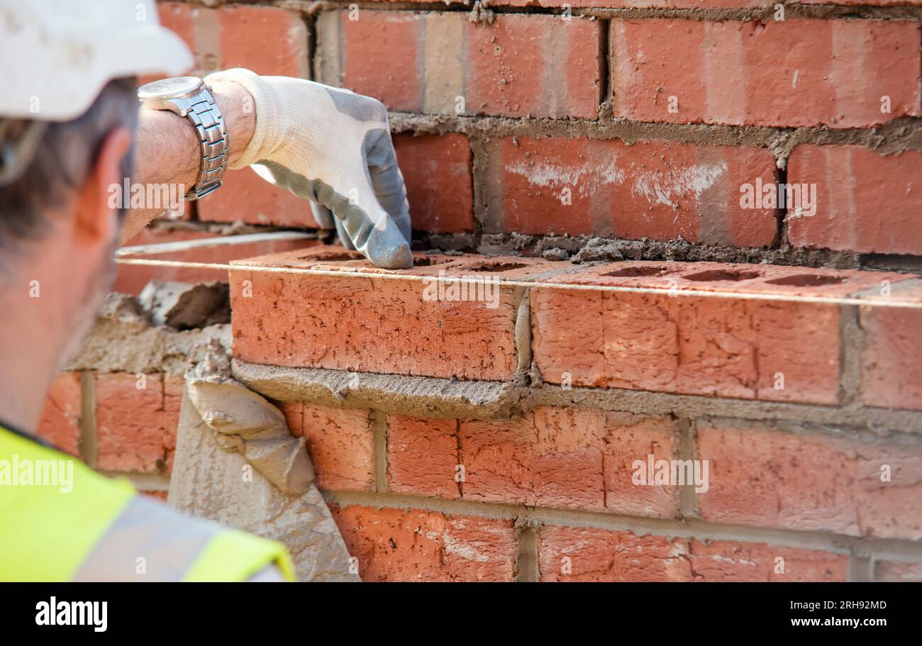 Close up of industrial bricklayer laying bricks on cement mix on