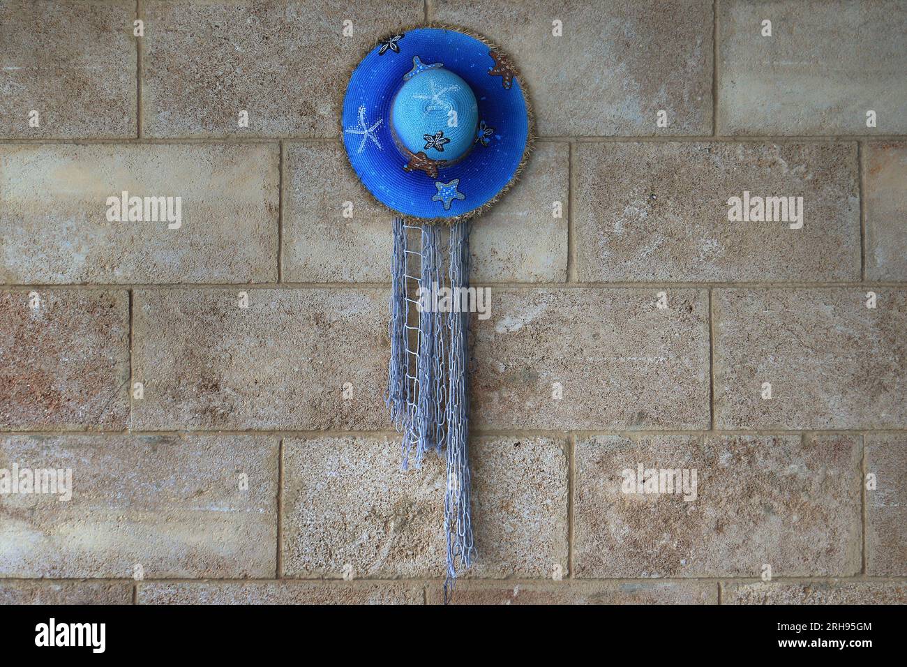 A blue straw hat hanging on a wall. Stock Photo