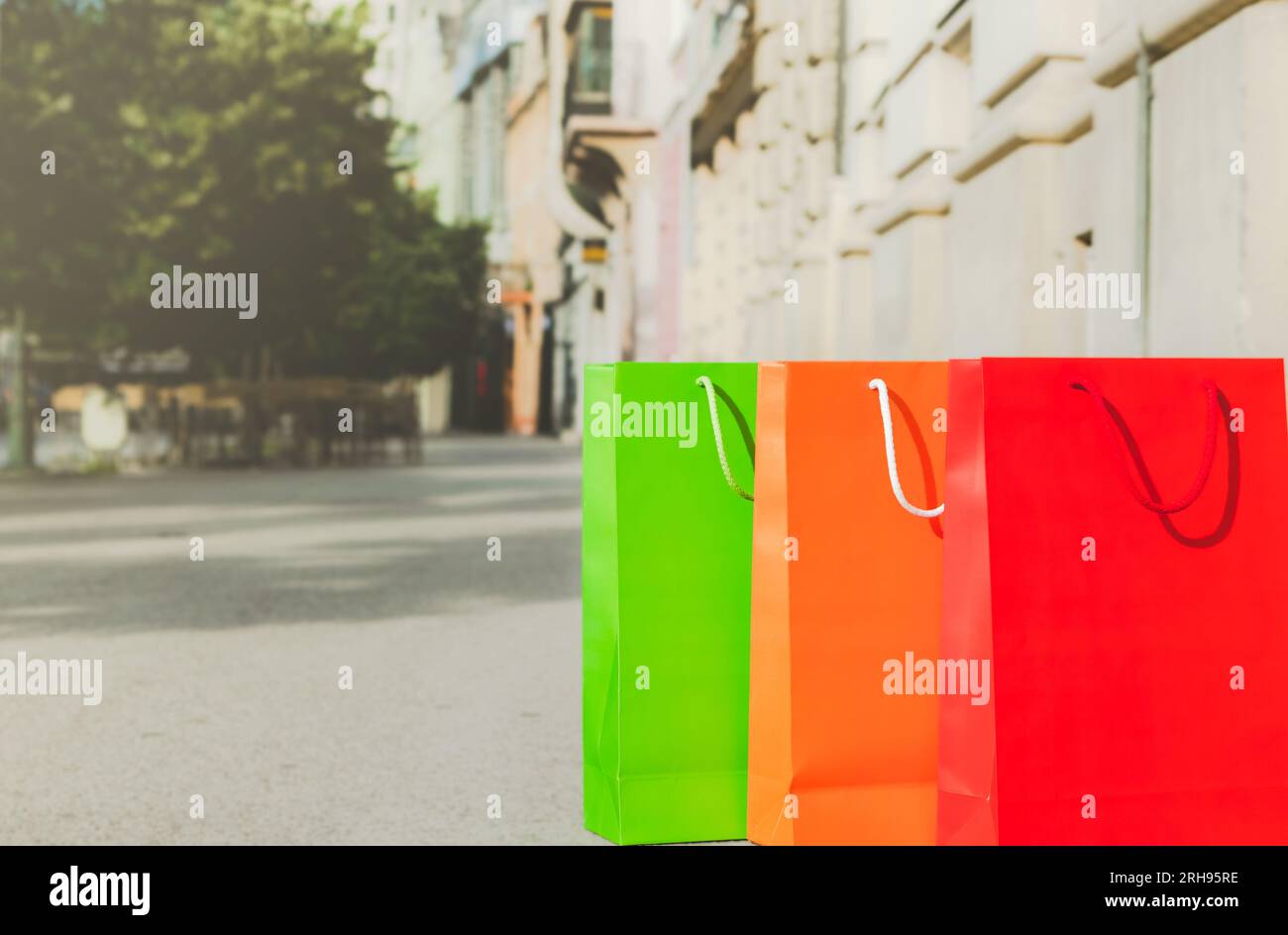 three colourful paper shopping bags on street Stock Photo