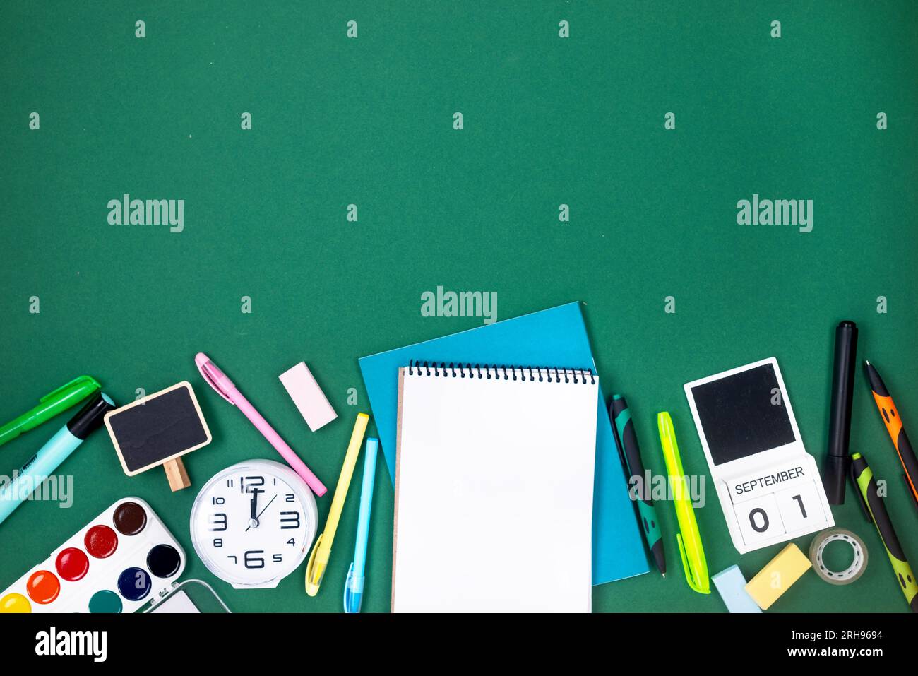 School notebook and various stationery on green background. Supplies ...