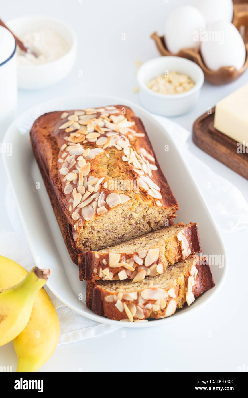 Banana bread with almonds on white plate on white background. Stock Photo