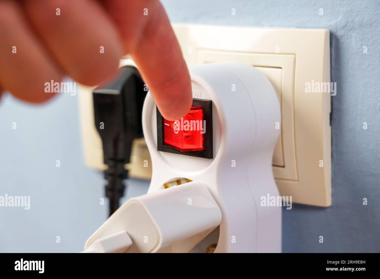 Turning off the red button of the electrical splitter to save electricity close up Stock Photo