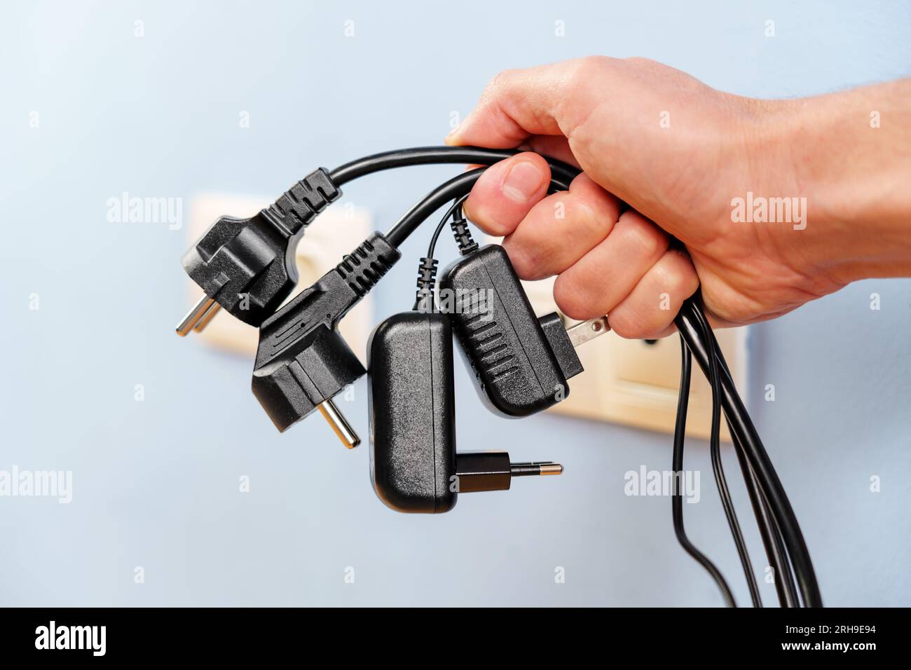 A bunch of disconnected electrical plugs with cables in a hand in room