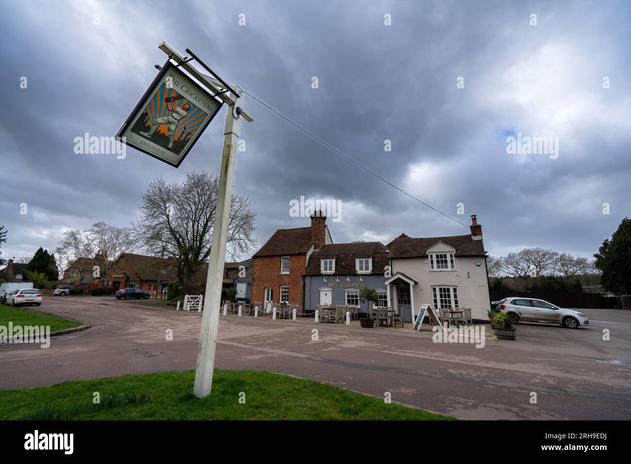 The Cricketers Pub in Sarratt, hertfordshire, UK on a blustery windy day dark moody sky sign swinging in wind Stock Photo