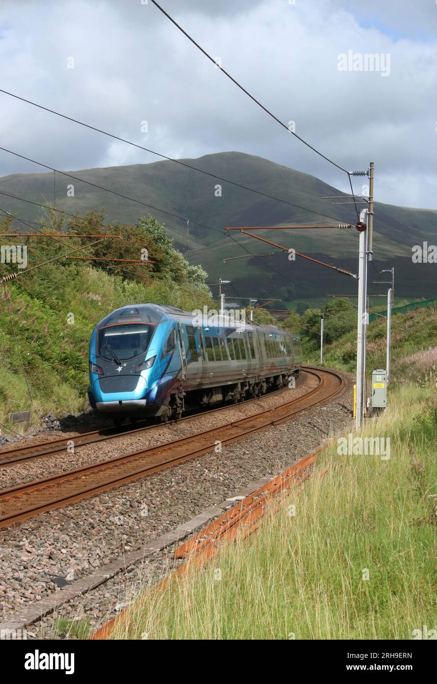 TransPennineExpress class 397 Civity emu rounds curve at Lowgill in Cumbria on West Coast Main Line with express passenger train, 11th August 2023. Stock Photo