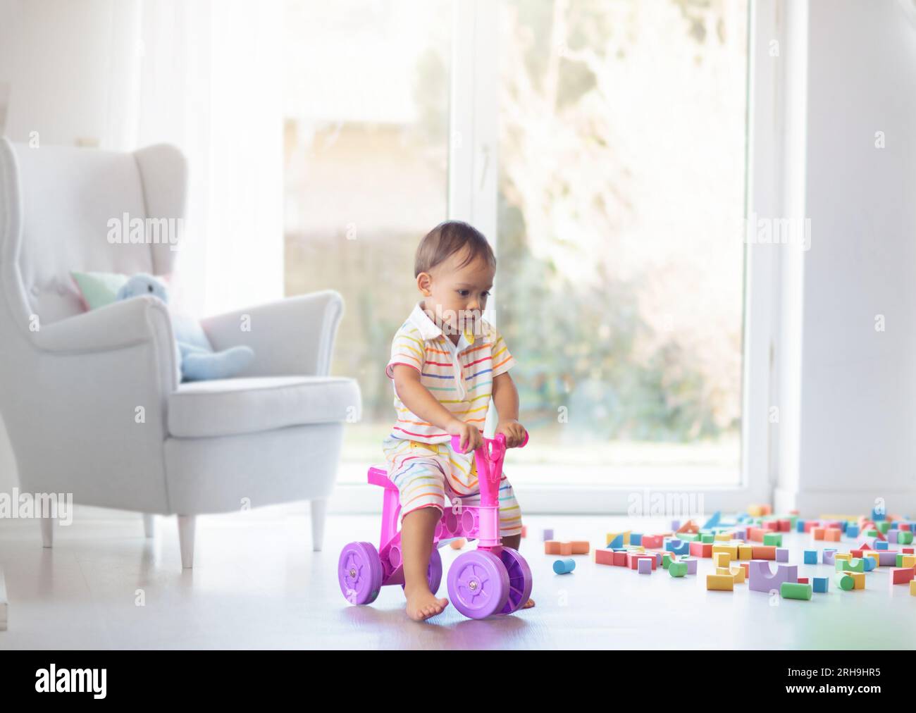 Adorable Asian baby boy on little push bike in kindergarten or