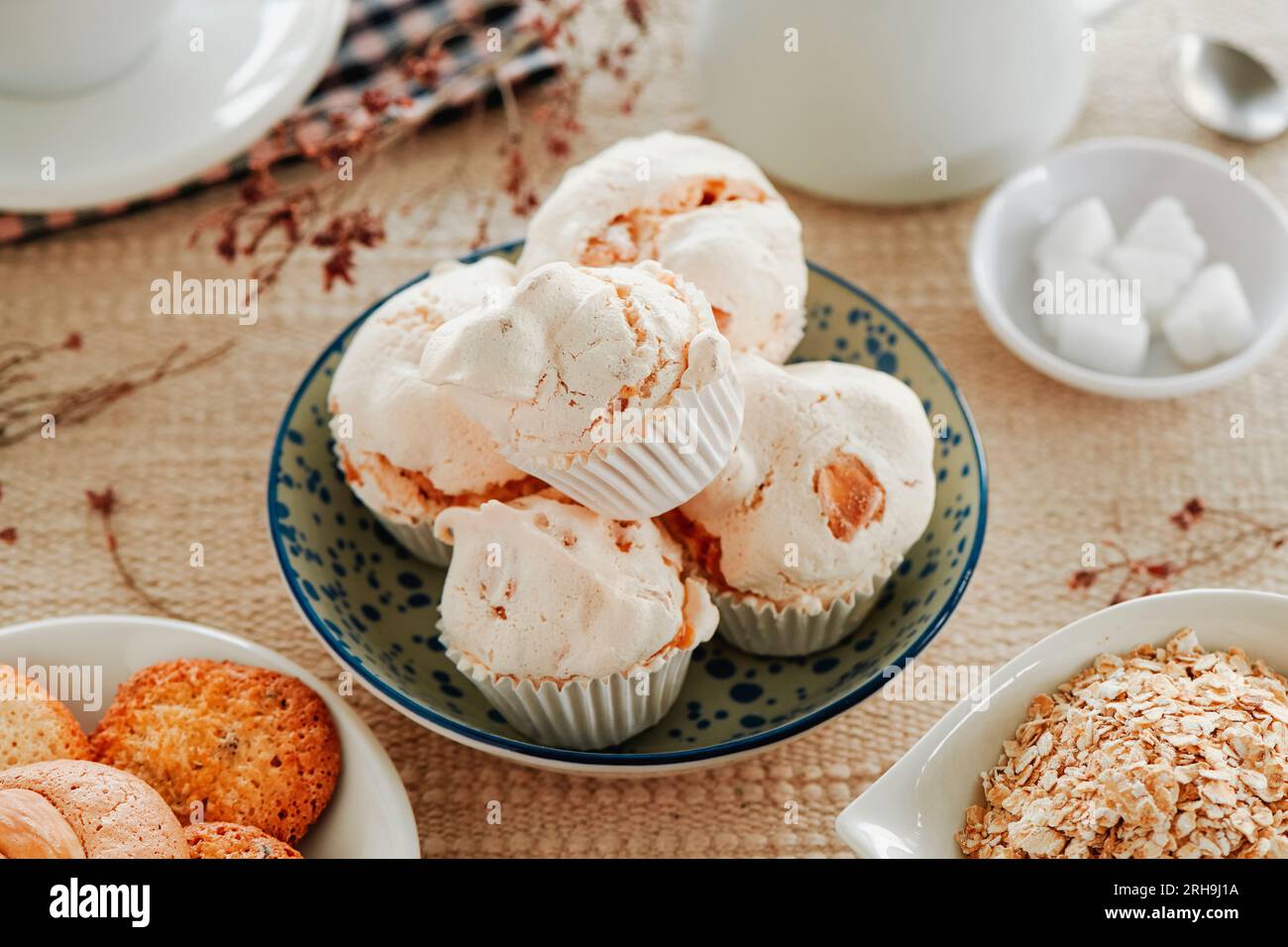closeup of some merengues almendrados, spanish baked meringues with almonds, in a white ceramic bowl on a table set with a brown tablecloth next to a Stock Photo