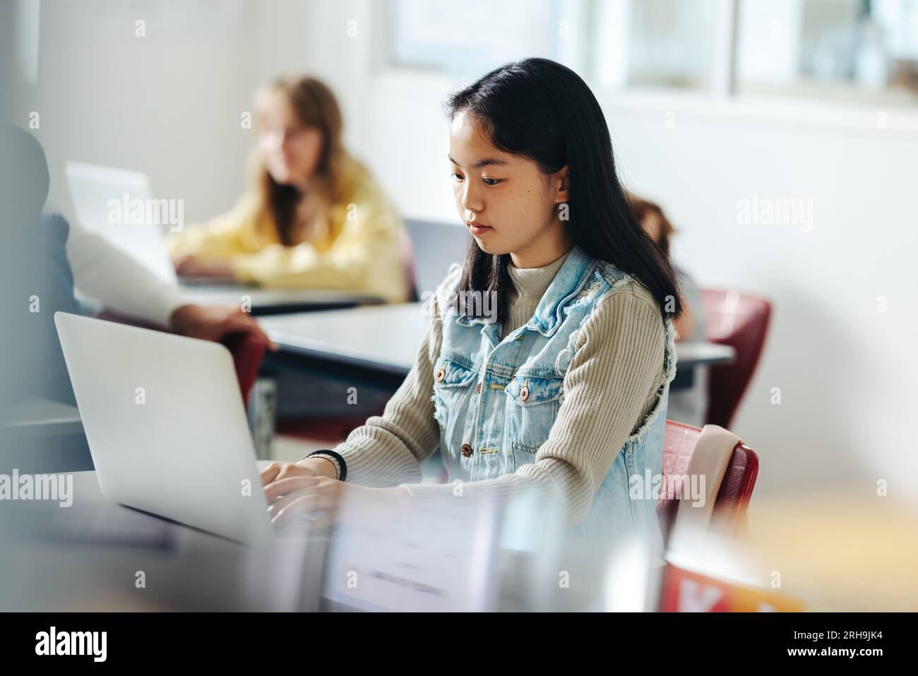 Digital literacy in action as a confident and capable elementary school girl takes part in a coding class using a laptop. Female student developing a Stock Photo