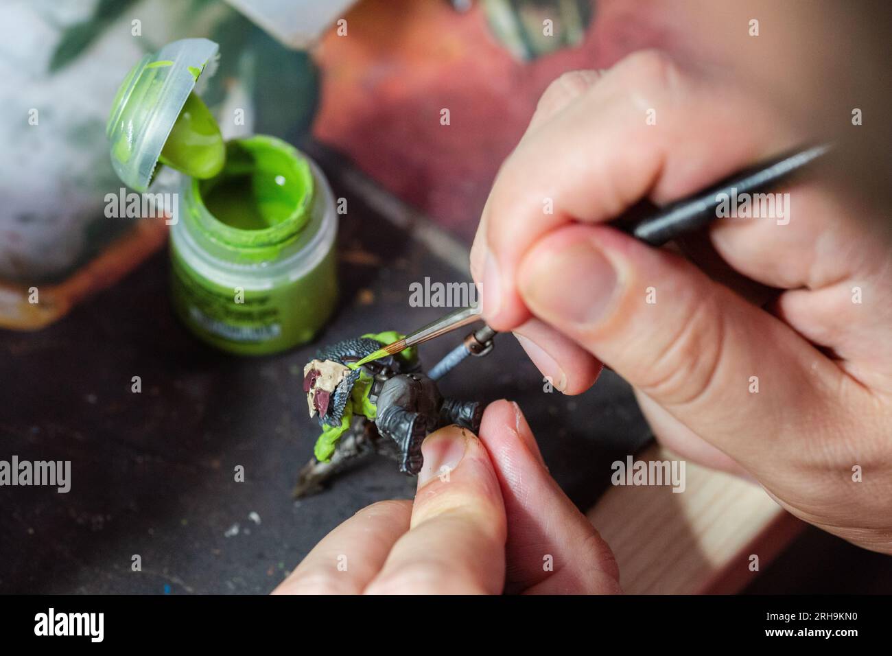 Close up of a man painting a Warhammer Squig Hog Boy with green paint