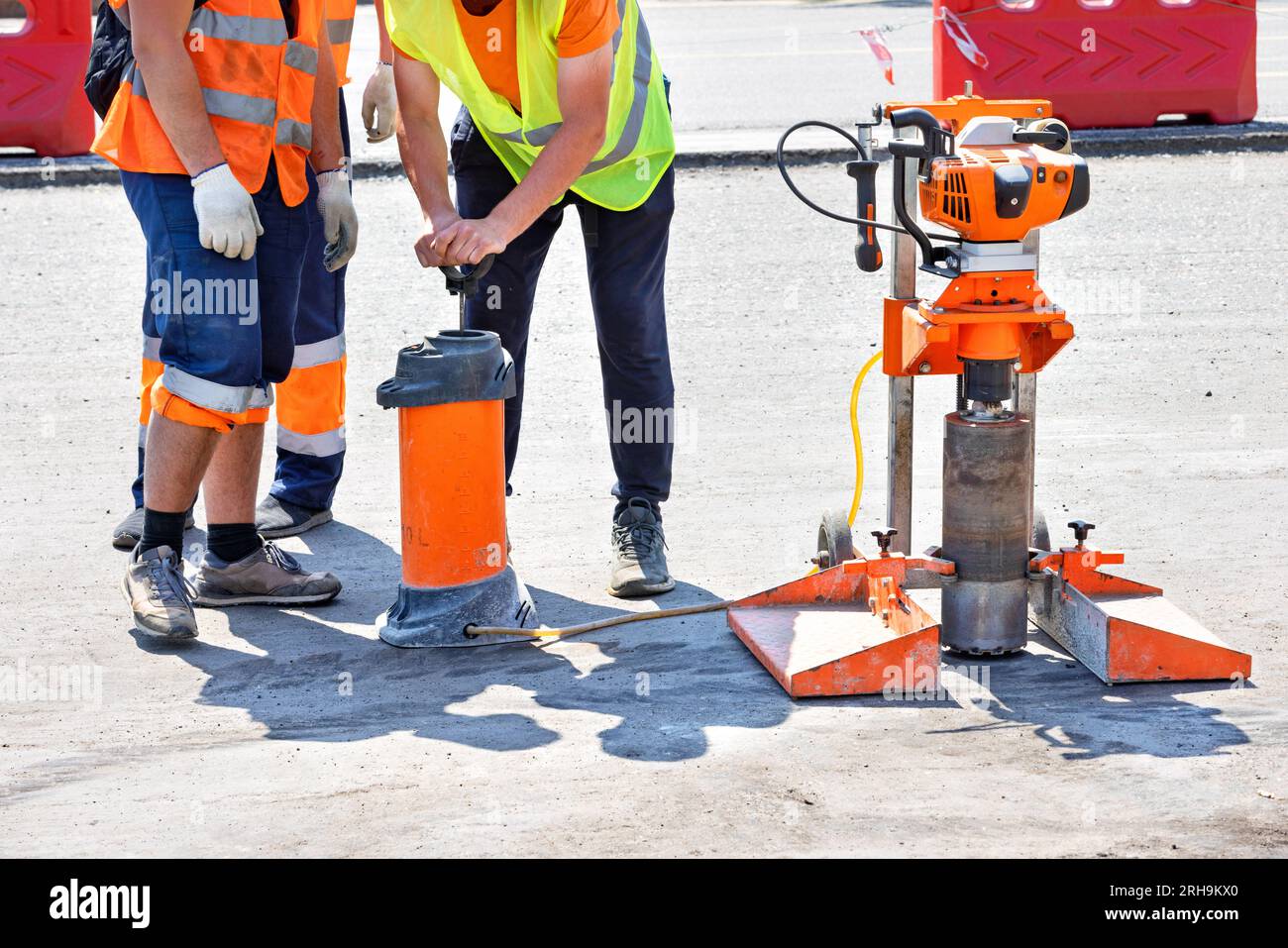 Road workers use a core drill to extract cores from an asphalt pavement during road repairs. Copy space. Stock Photo
