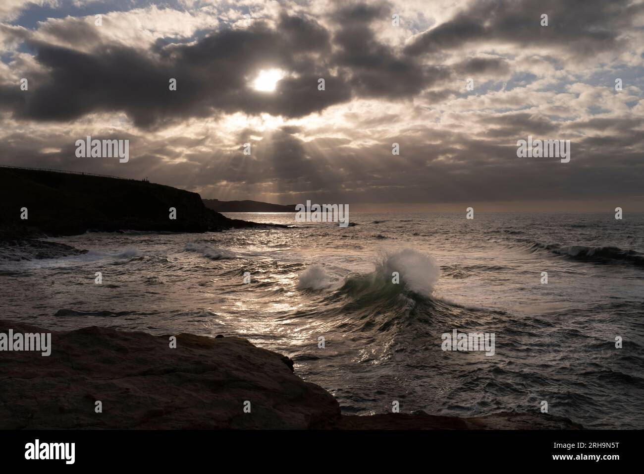 View of a sunset with the sun through the clouds over the Cantabrian Sea. Golden hour. Stock Photo