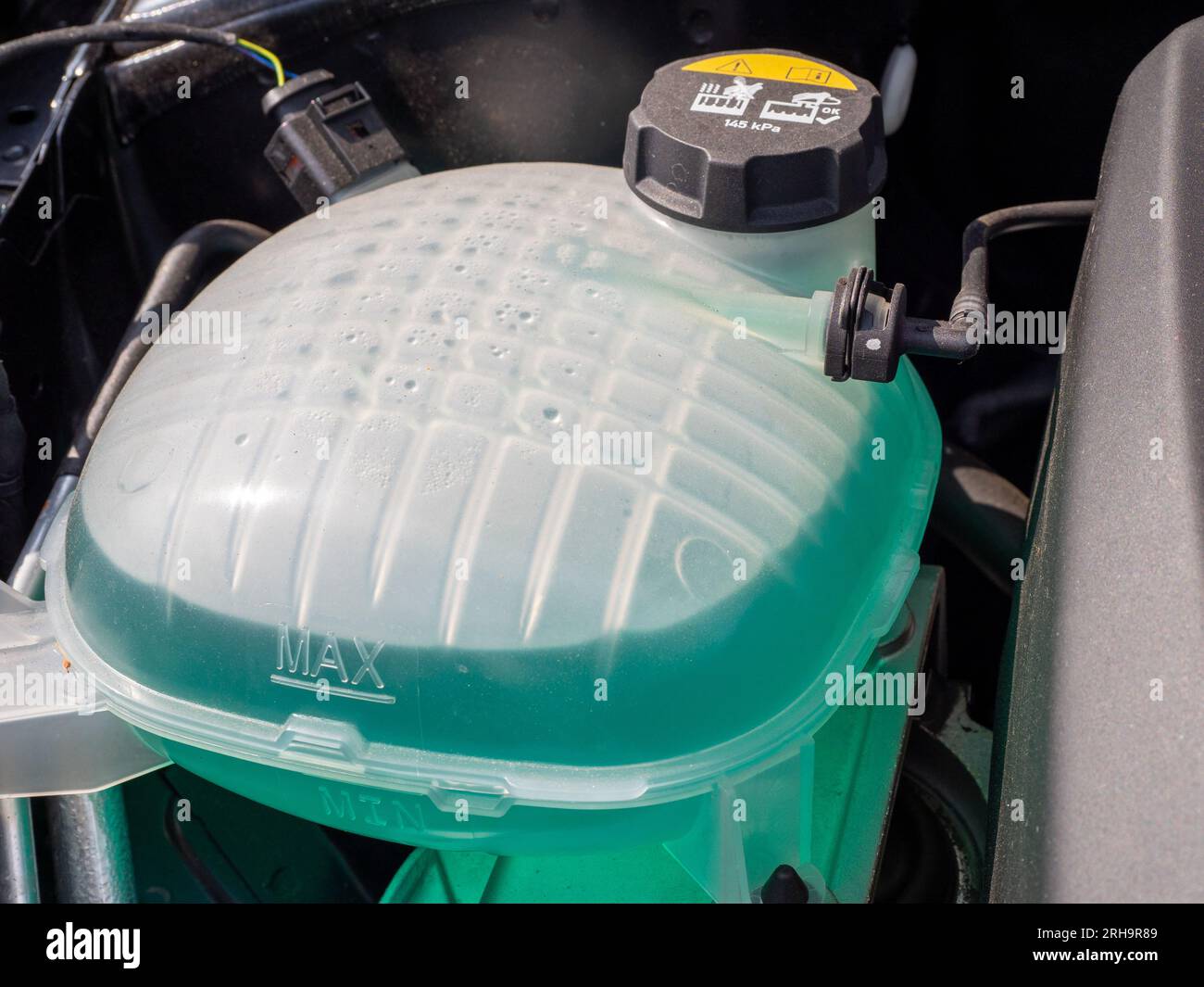 Tank of liquid antifreeze of the cooling system of the car radiator system. Tank with antifreeze close-up. Stock Photo