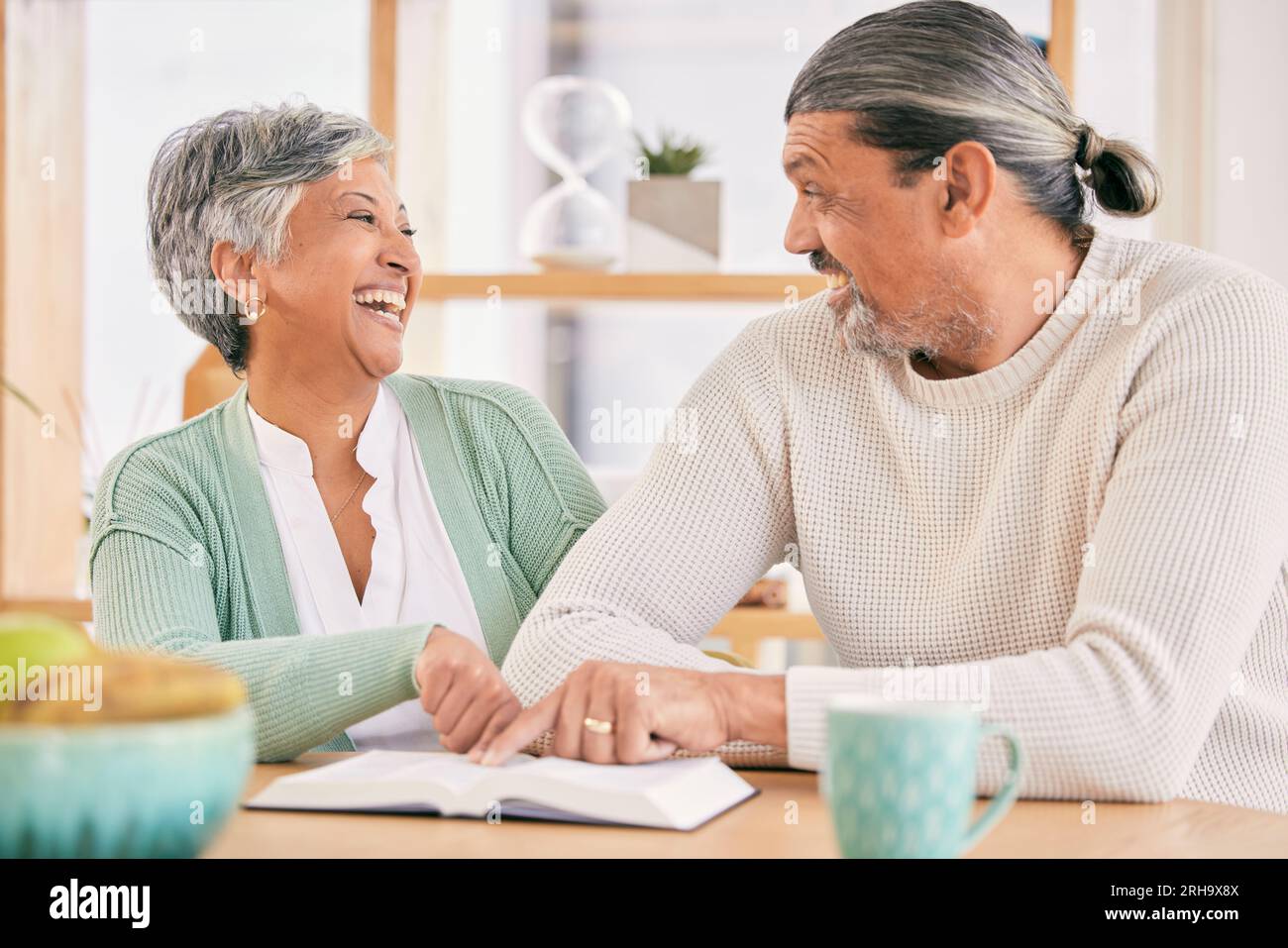 Reading, book and senior couple at home with bible study and religion together in marriage. Laughing, happy and elderly people with worship, learning Stock Photo
