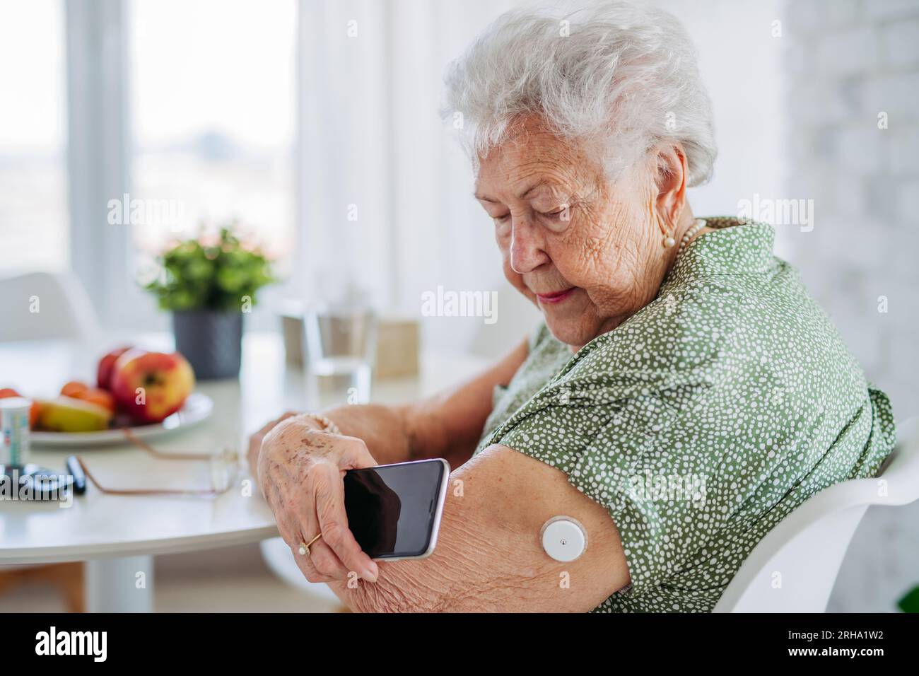 Diabetic senior patient checking blood glucose level at home using continuous glucose monitor