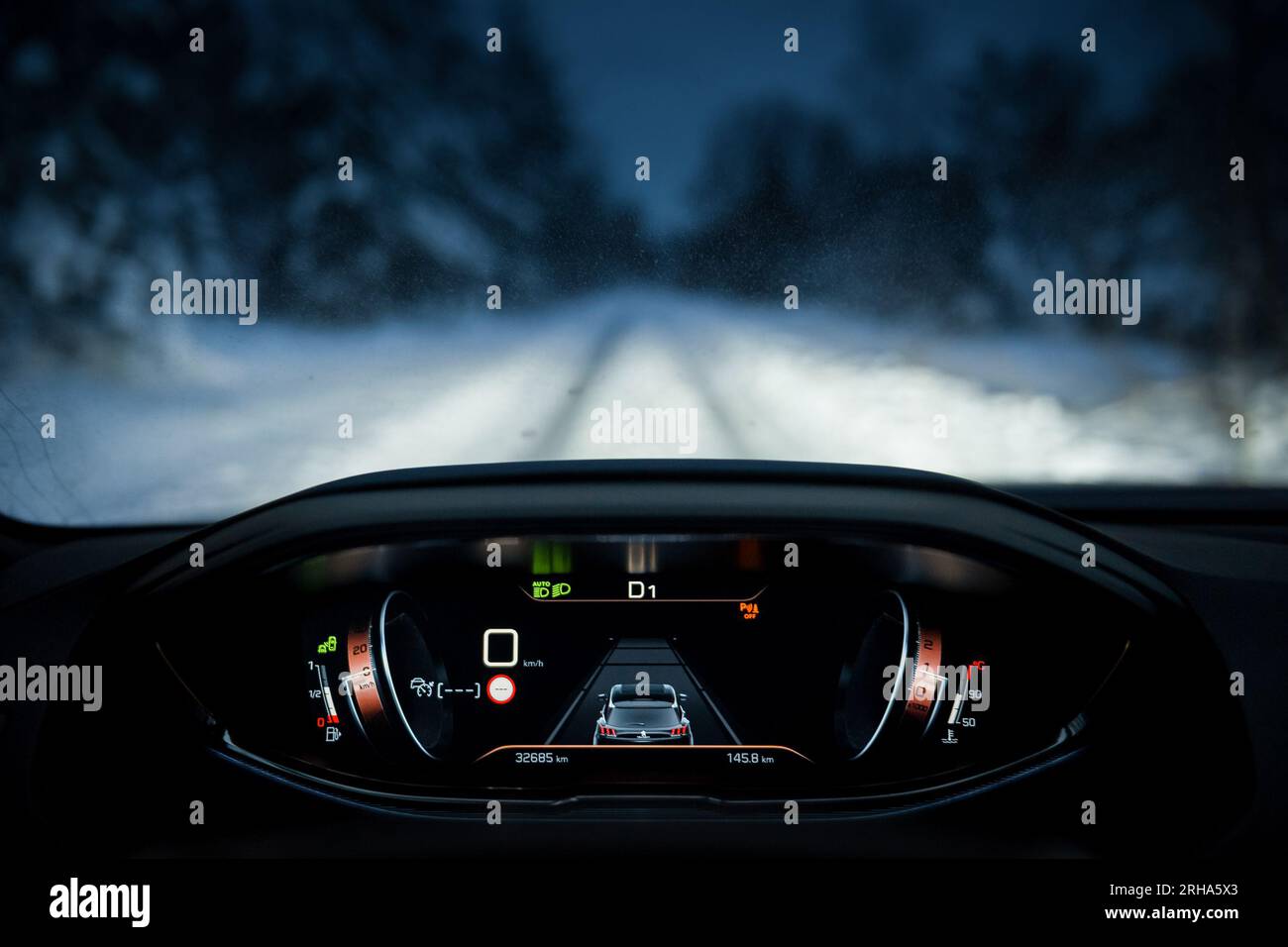 first person view of driving Peugeot 3008 through winter forest. Dahboard, gauge cluster in focus and snow covered road and trees in the background Stock Photo