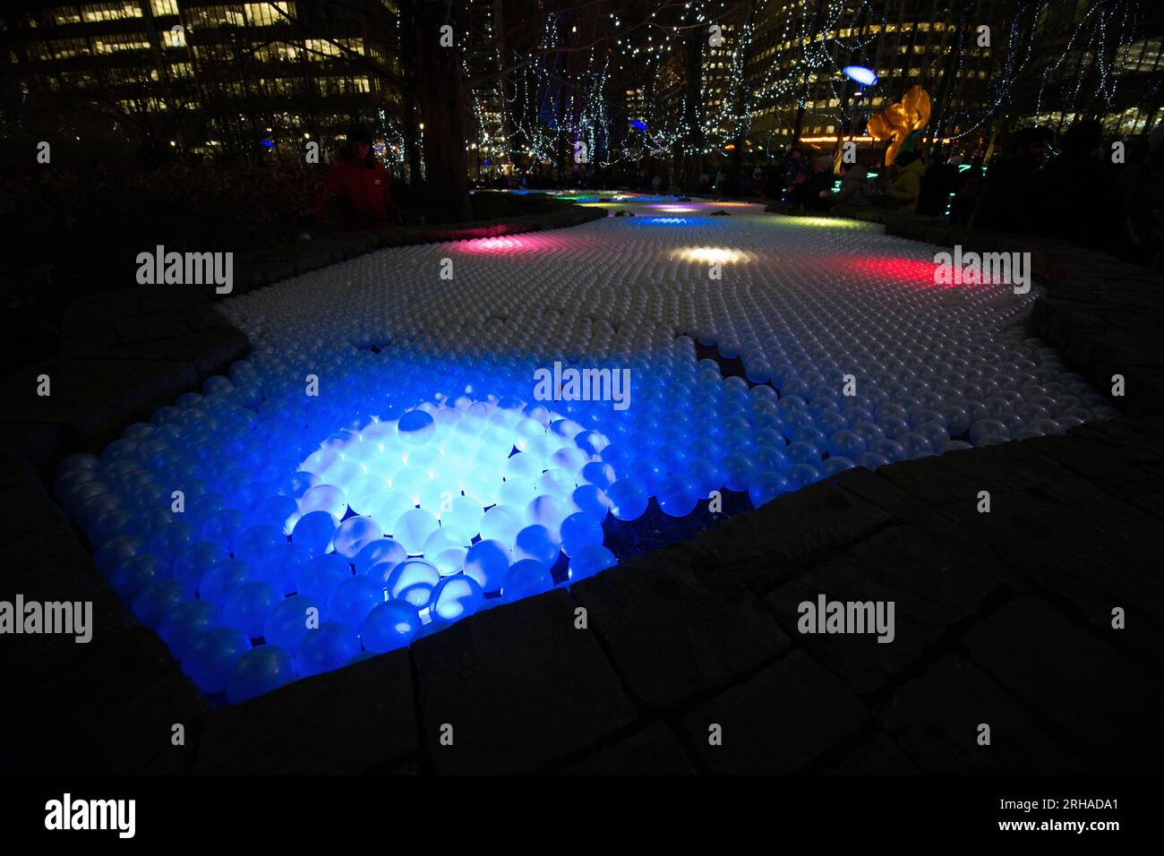Illuminated plastic balls floating on water - Canary Wharf Winter Lights art festival 2020 Stock Photo
