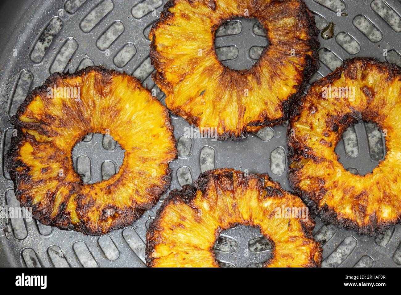 Pineapple rings fried in an electric air fryer appliance, in a metal