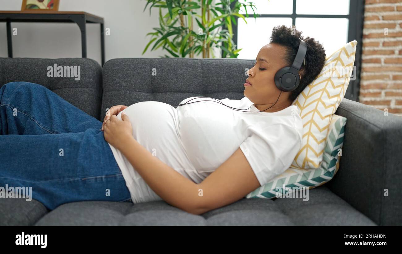 Young pregnant woman listening to music sleeping on sofa at home Stock ...