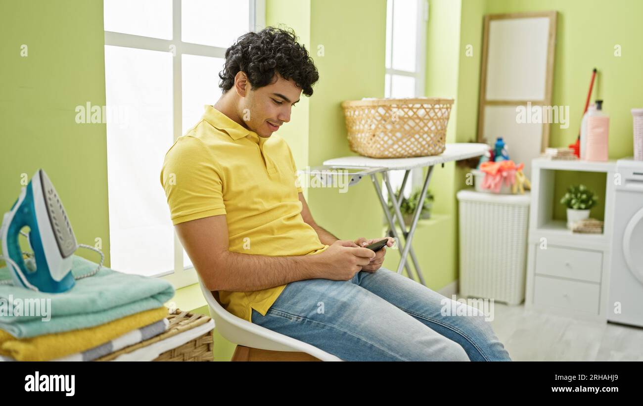 Young latin man playing video game waiting for washing machine at laundry  room Stock Photo - Alamy