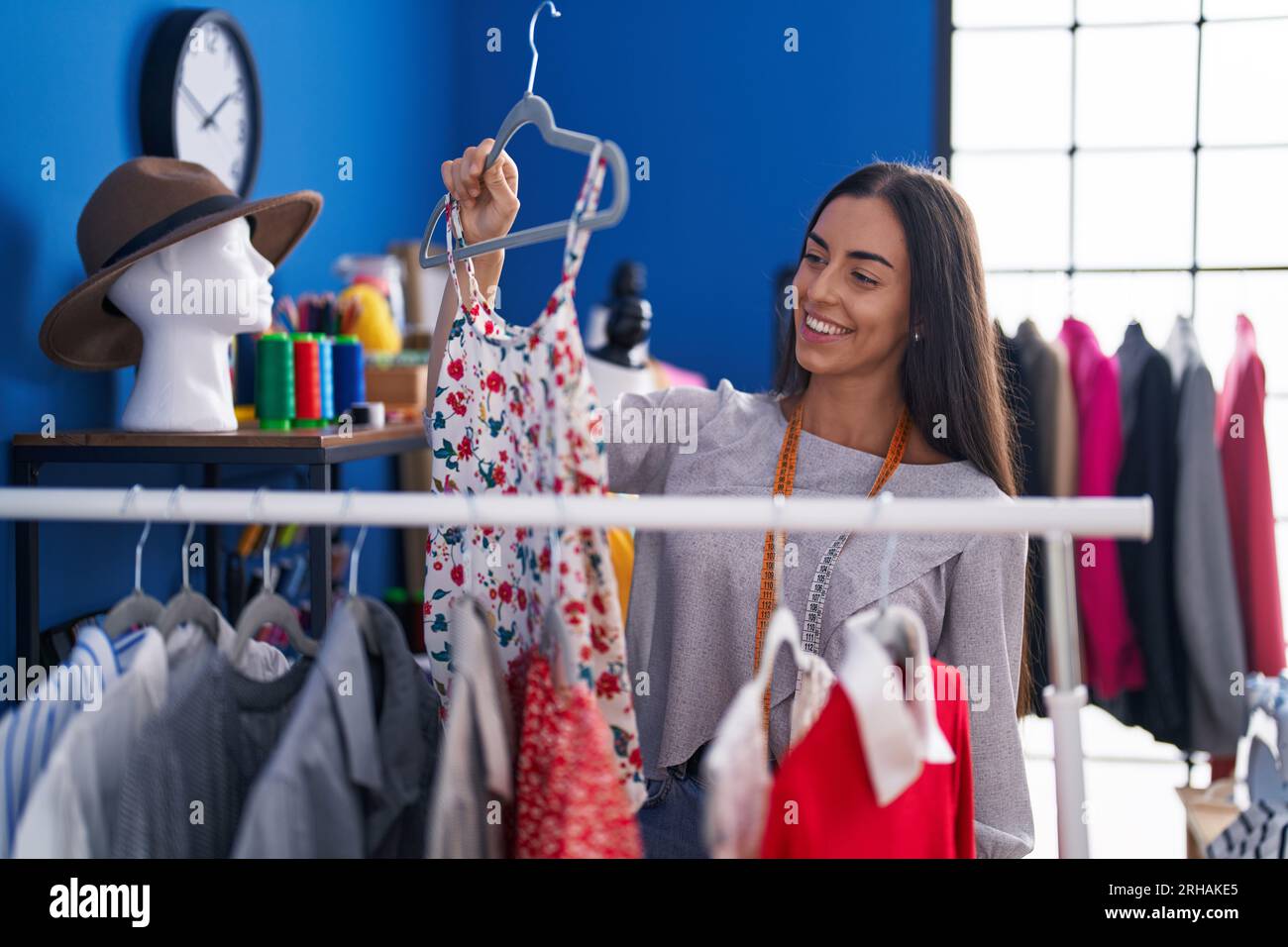 Hispanic Rack Young beautiful hispanic woman tailor smiling confident holding clothes ...