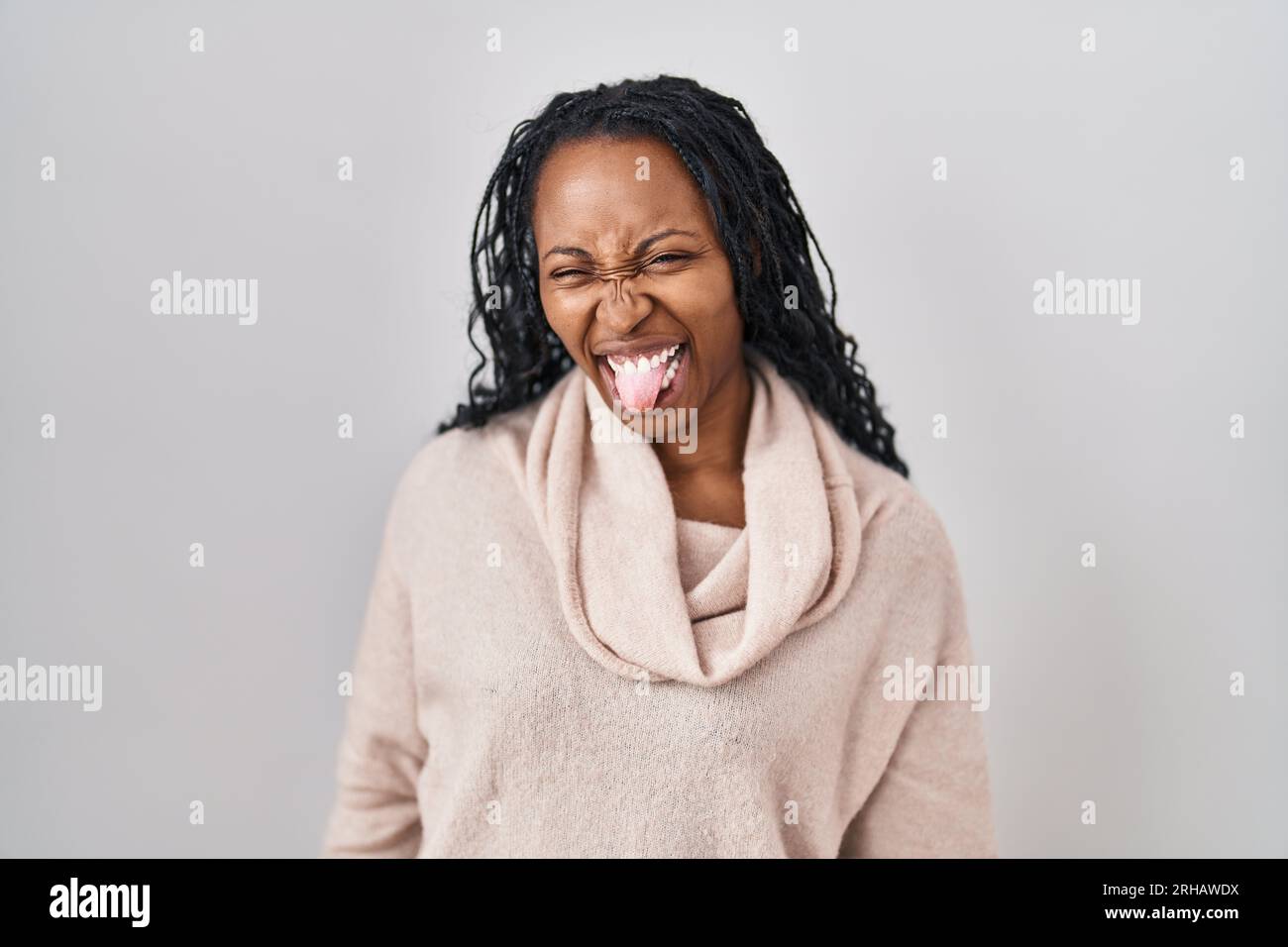 African woman standing over white background sticking tongue out happy ...