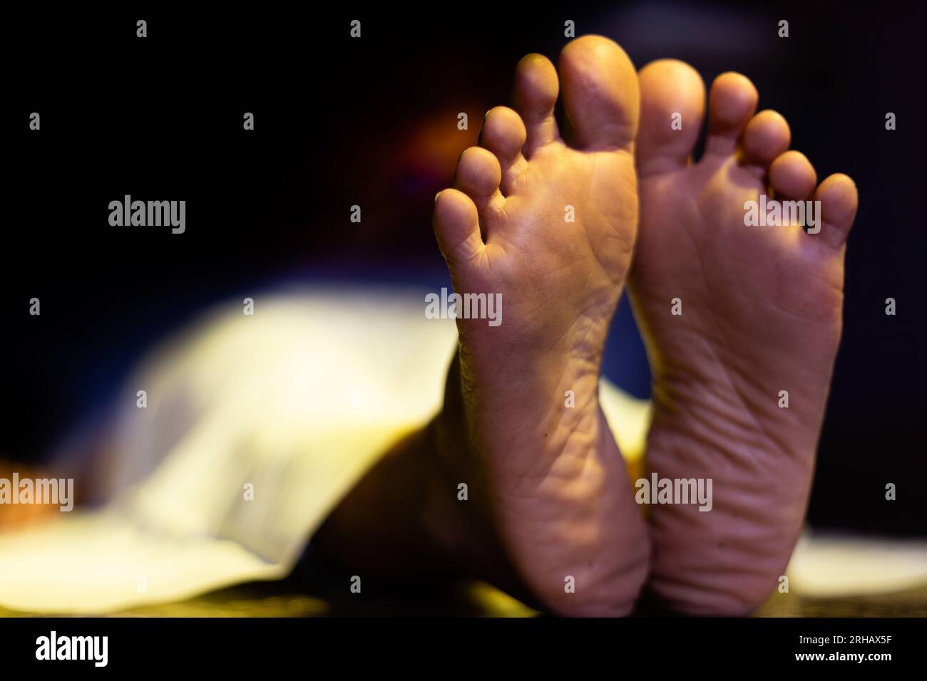 Feet of an Indian or Asian female dead body lying on floor in a dark room Stock Photo