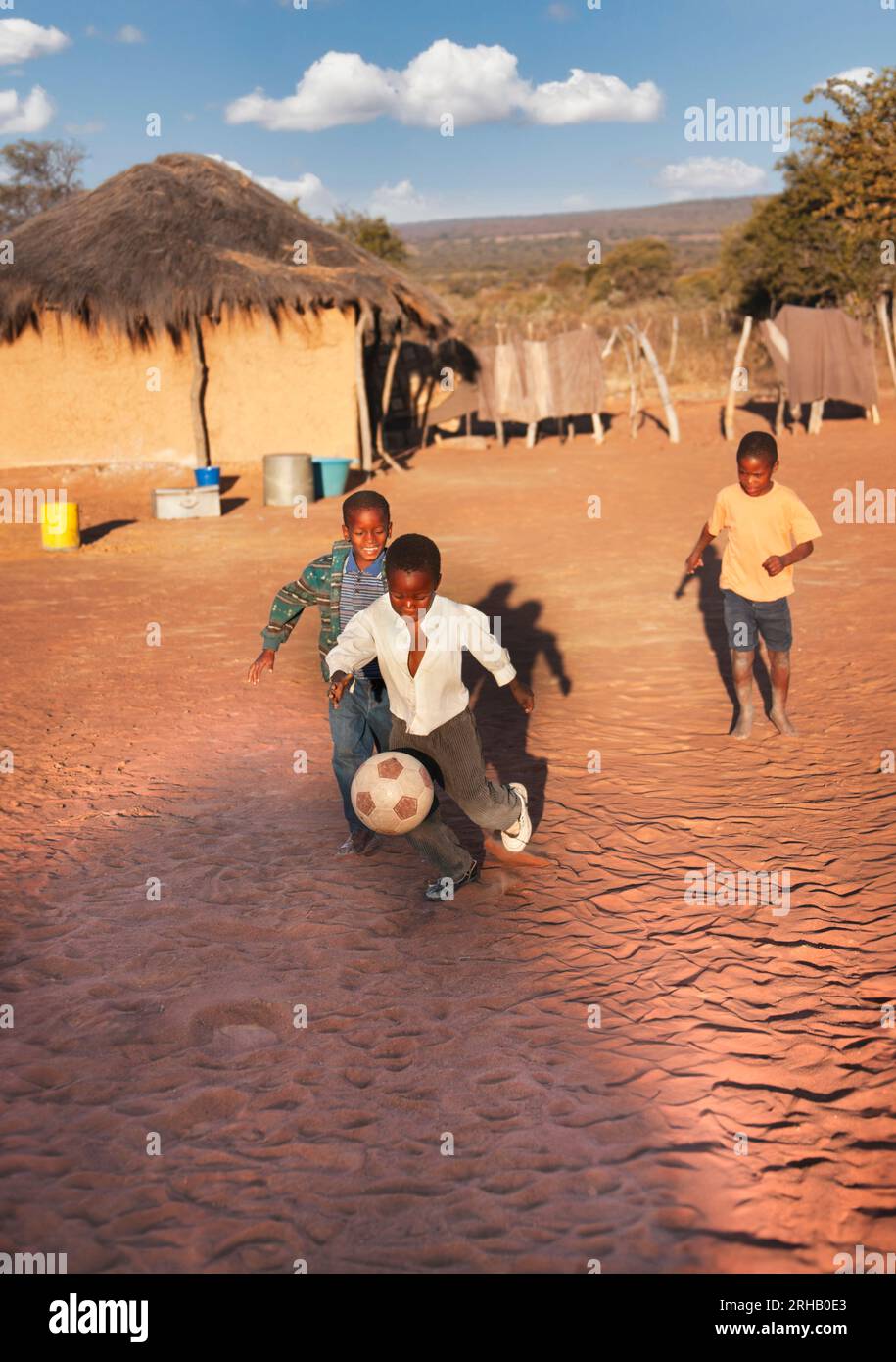 African village children playing football on the dirt in the yard Stock Photo
