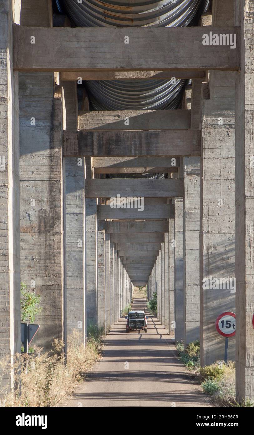 Vehicle crossing the road under Acedera Aqueduct, Vegas Altas del Guadiana, Badajoz, Extremadura, Spain Stock Photo
