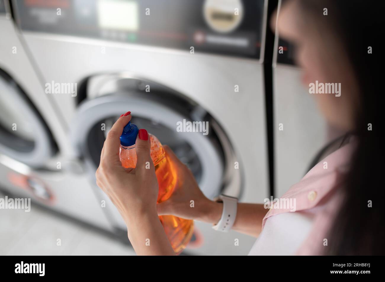 Woman in laundromat putting cleaning detergent Stock Photo Alamy