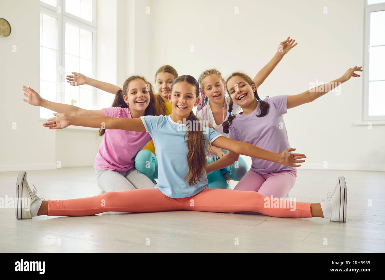 Group of happy flexible children sitting on floor at sport dance school