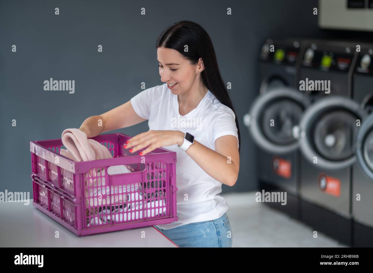 Woman in the public room to wash her cloths, self service commercial laundry and drying machine in a public room. Stock Photo