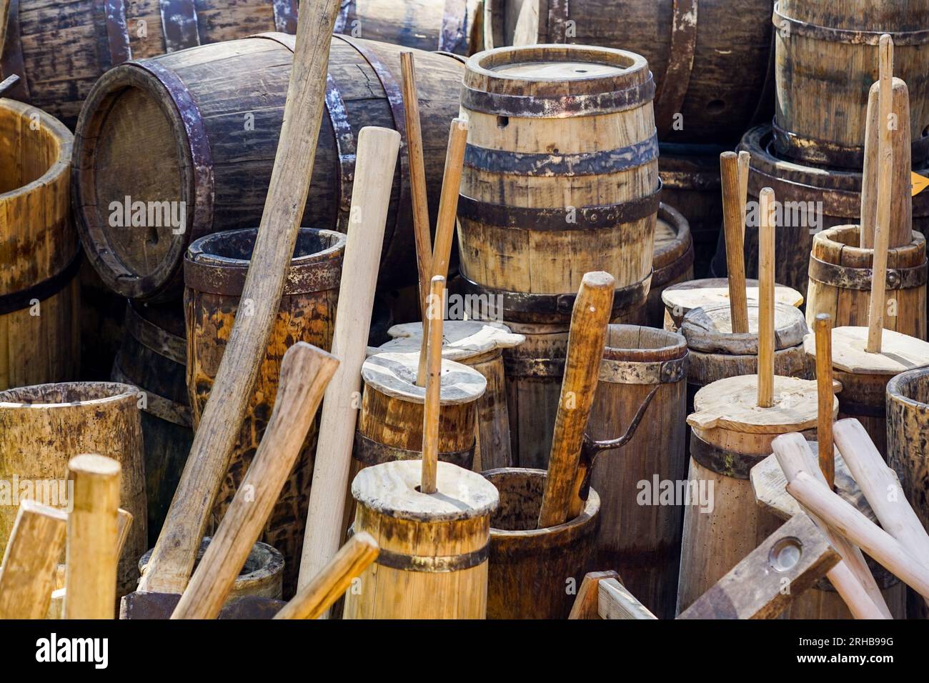 Authentic old wooden barrels of various sizes with metal hoops, butter churns, wooden utensils Stock Photo