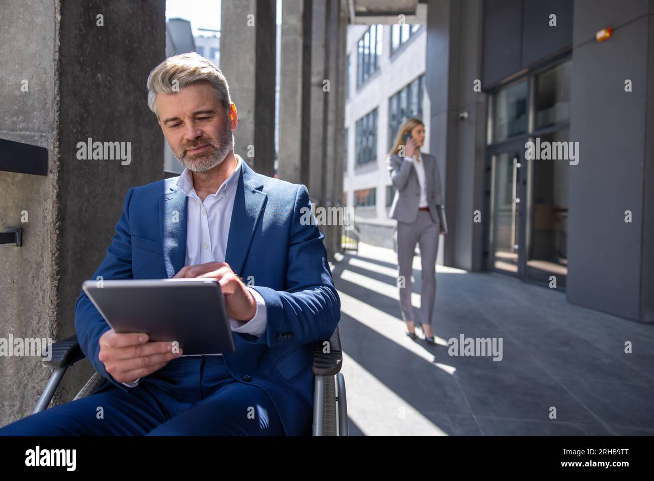 Executive business man in wheelchair with tablet using mobile device ...