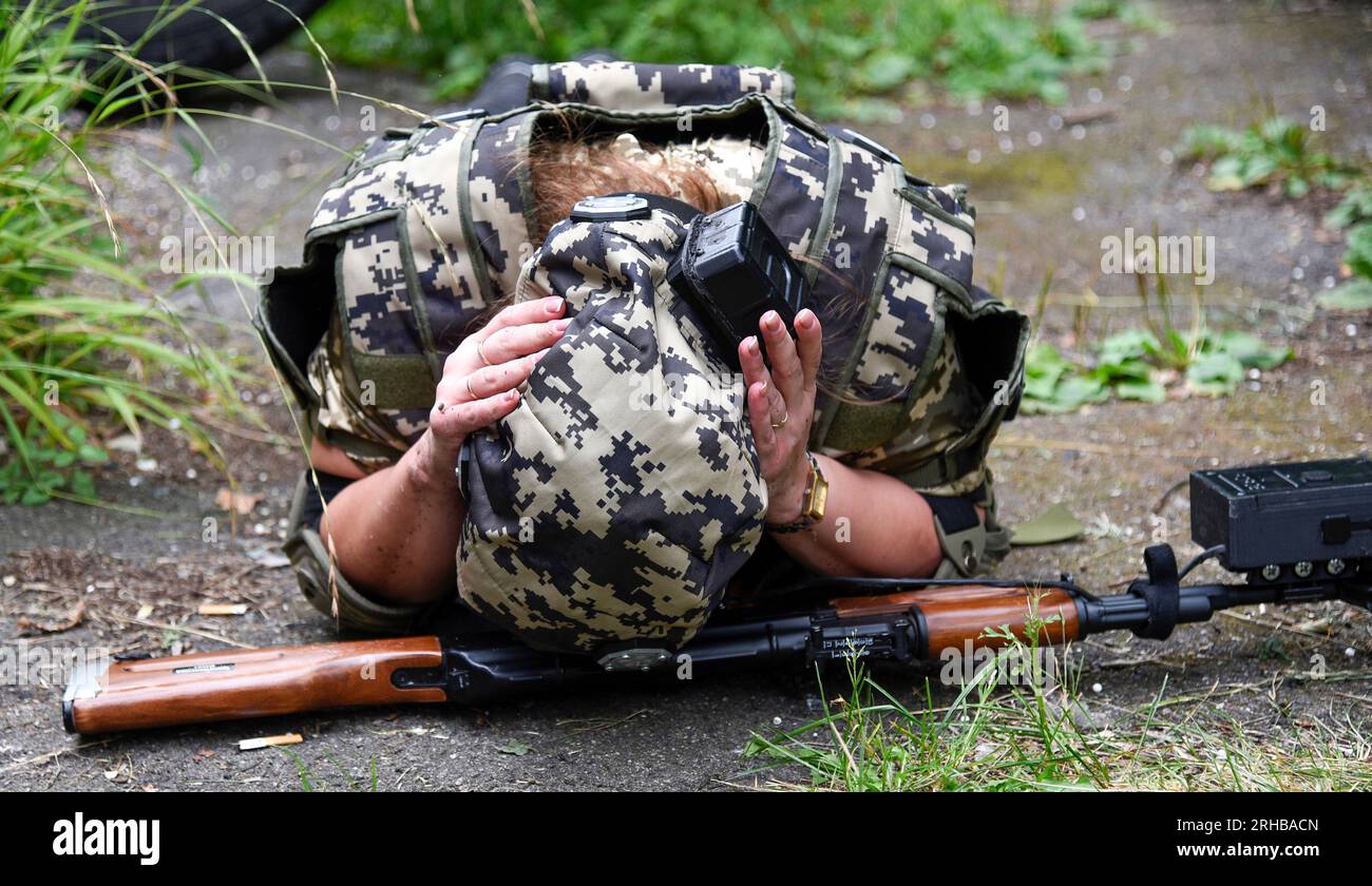 KYIV REGION, UKRAINE - AUGUST 11, 2023 - A woman lies on the ground face down during a training session for civilians on the preparation for national Stock Photo