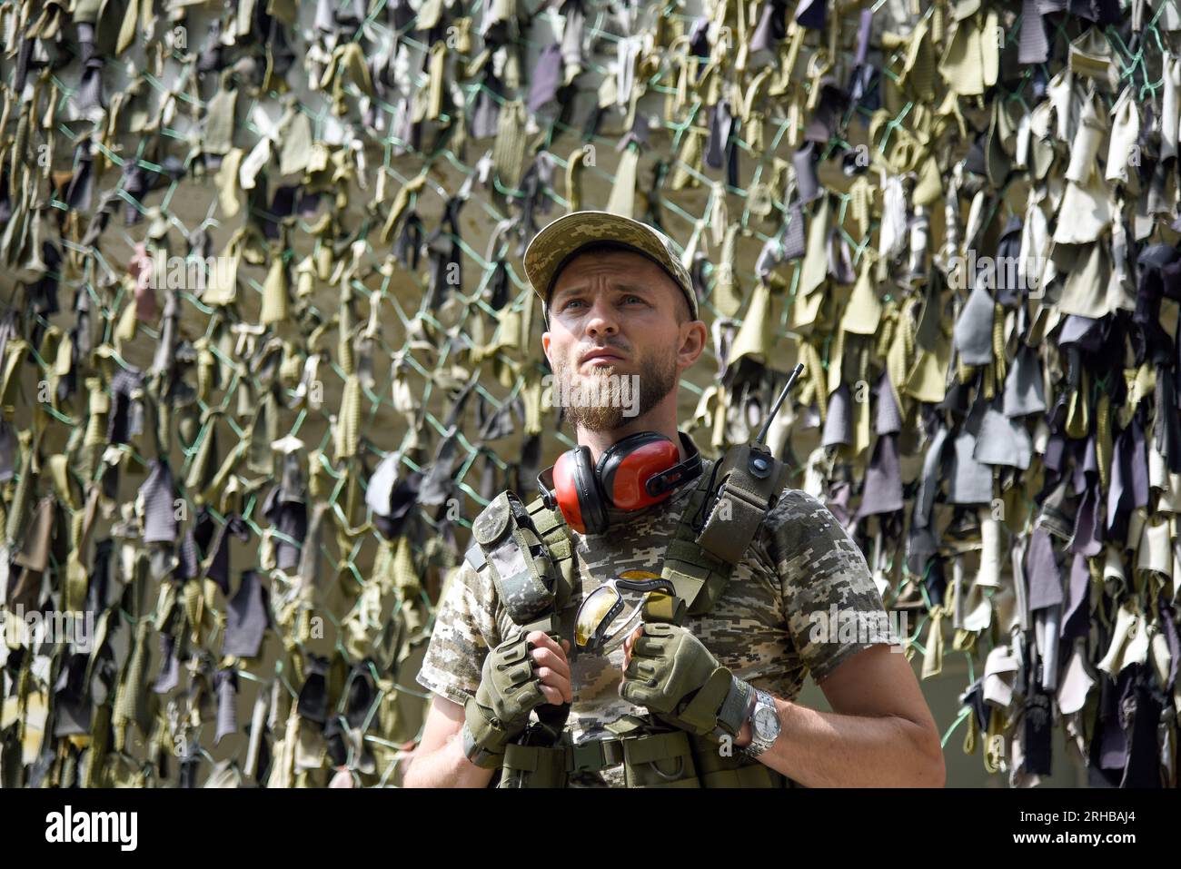 KYIV REGION, UKRAINE - AUGUST 11, 2023 - A man stands before a camouflage net during a training session for civilians on the preparation for national Stock Photo