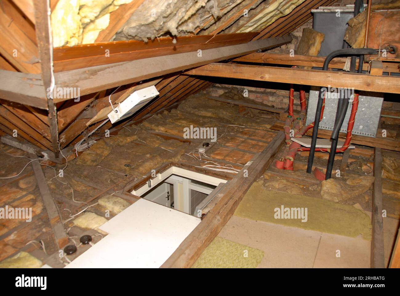 Interior of domestic loft with insulation and cold water tank and feeder tank for central heating and access hatch open Stock Photo
