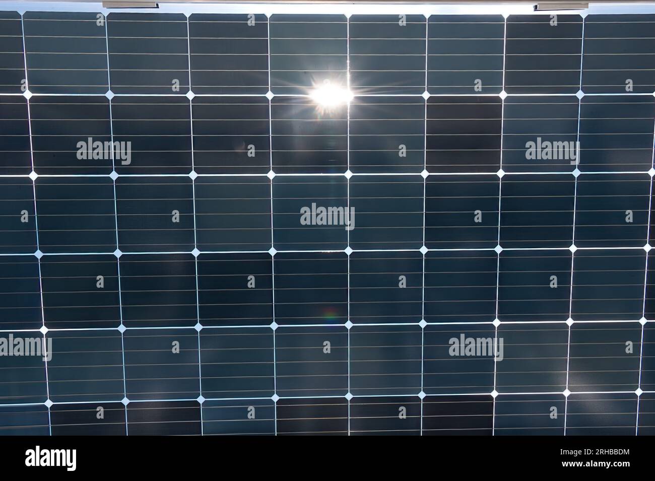 Close up of a solar panel reflecting the sun. It converts sunlight into electricity by using photovoltaic cells. Stock Photo