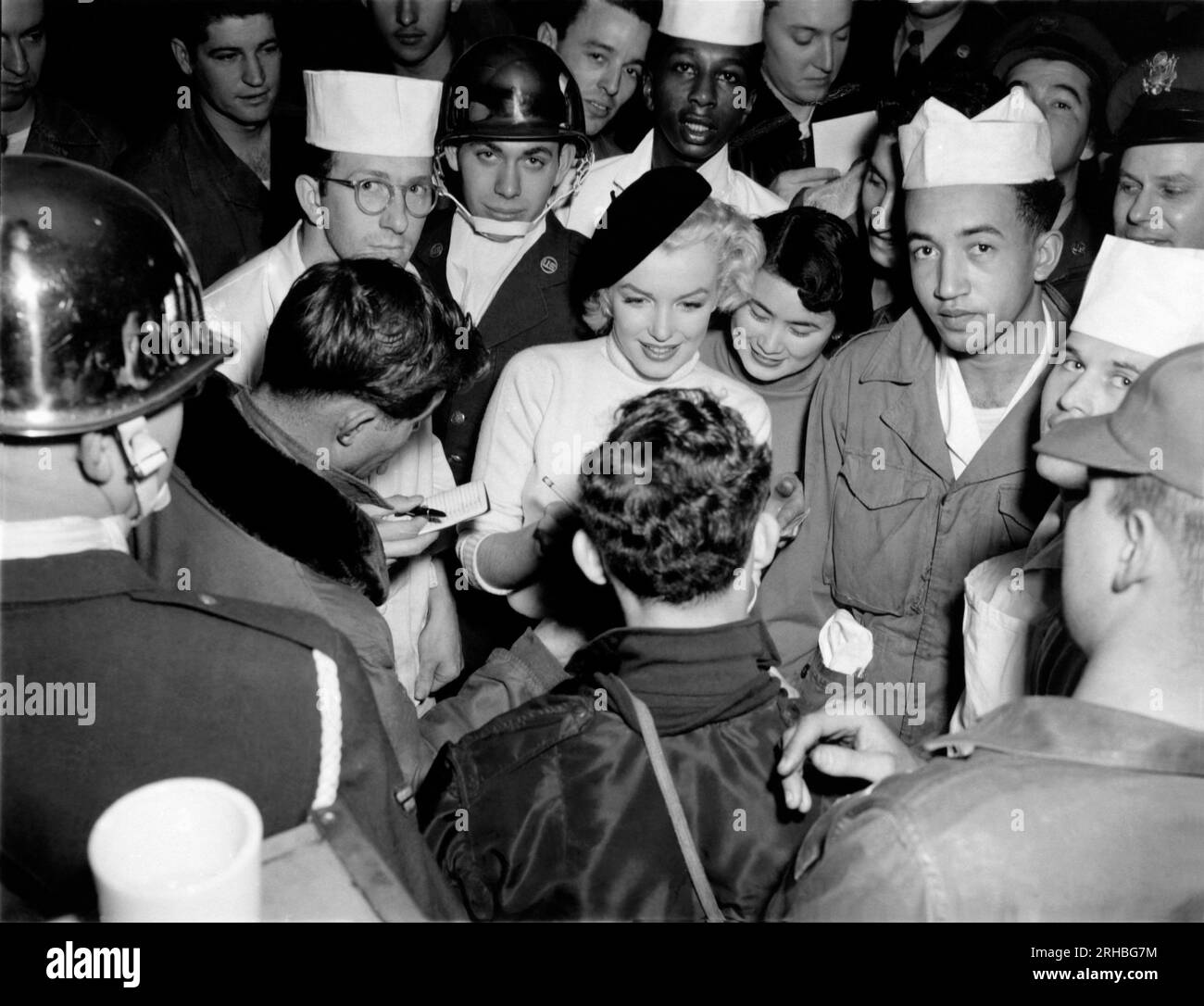 Korea:  February, 1954. Marilyn Monroe visits the troops in Korea, entertaining over 100,000 soldiers in 10 different locations. Here she is signing an autograph for a happy soldier. Stock Photo