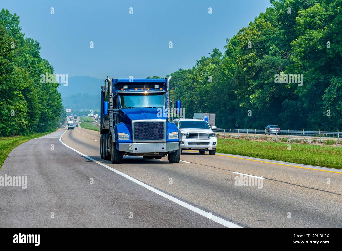 Horizontal shot of a heavy blue dump truck on an interstate highway ...