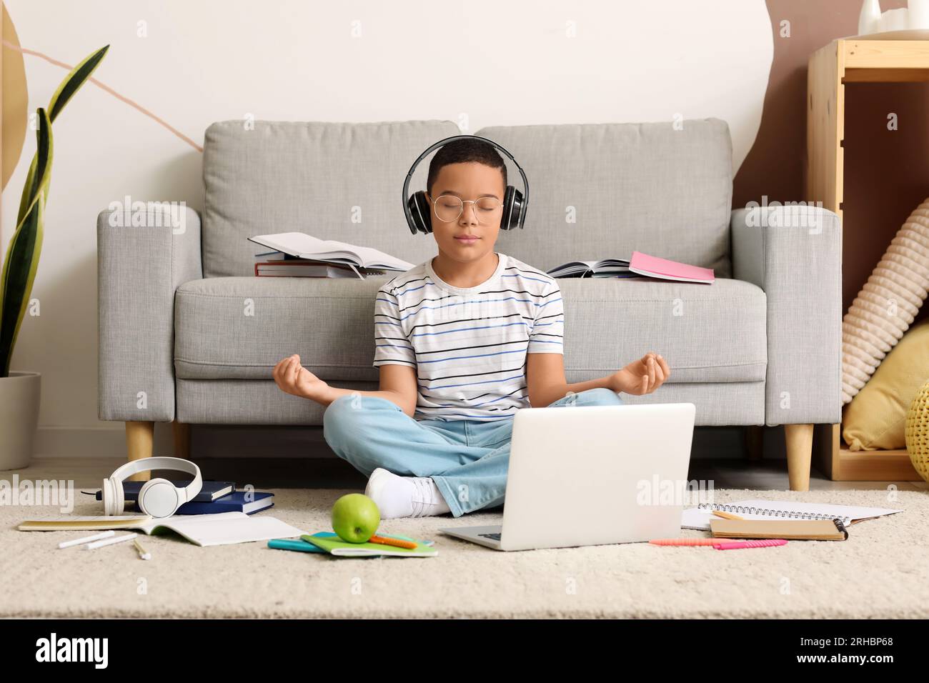 Little African-American boy in headphones meditating while studying at home Stock Photo