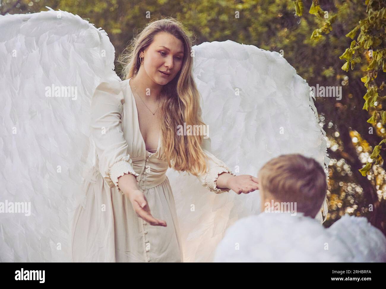 Beautiful girl angel with her son in the evening garden Stock Photo