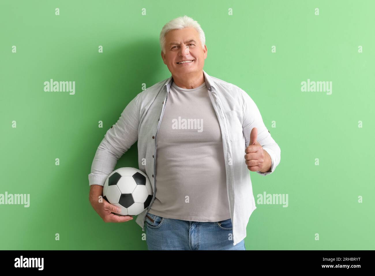 Mature man with soccer ball showing thumb-up on green background Stock ...