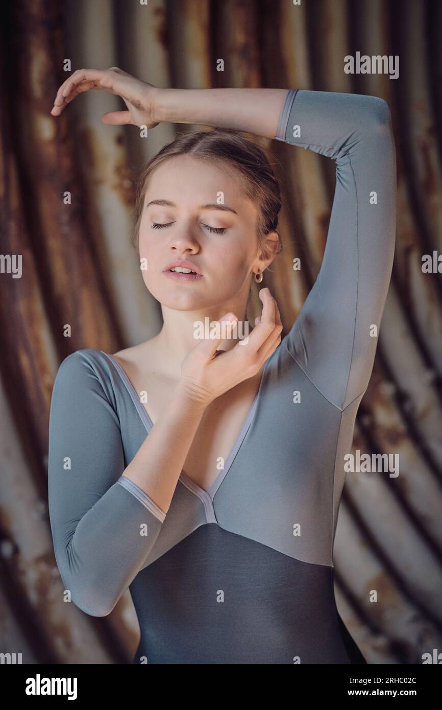 Beautiful female ballet dancer dancing with closed eyes and raised arm