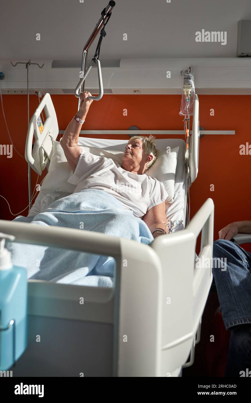 Sick senior female patient with short white hair in medical robe lying