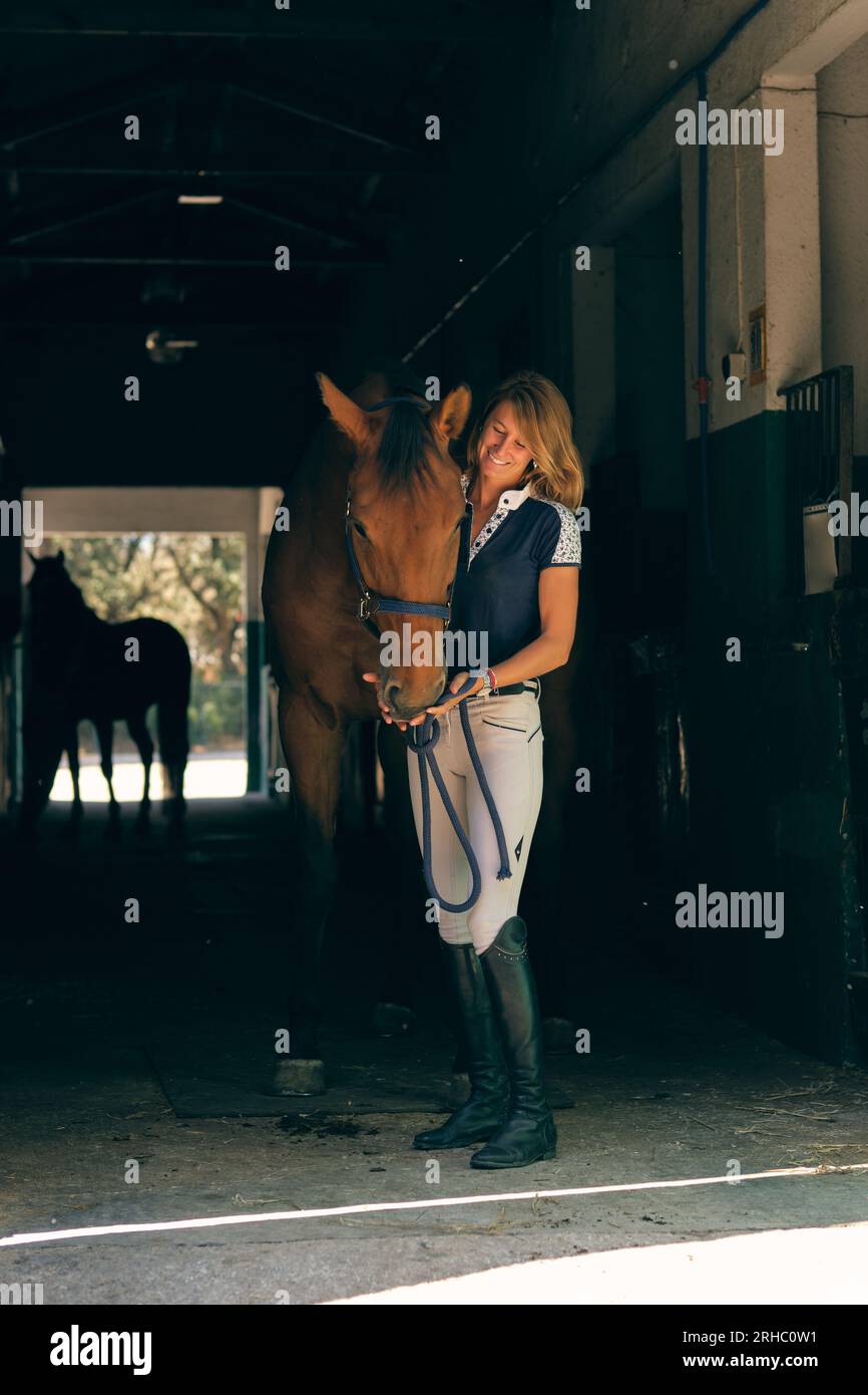 Positive female rider standing with chestnut horse licking her hands in