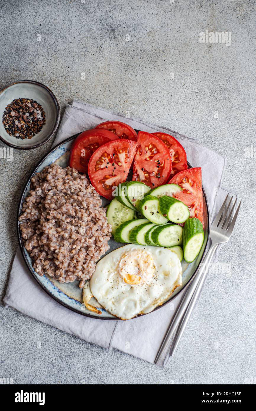 Overhead view of a healthy lunch plate with buckwheat, cucumber, tomato and a fried egg Stock Photo