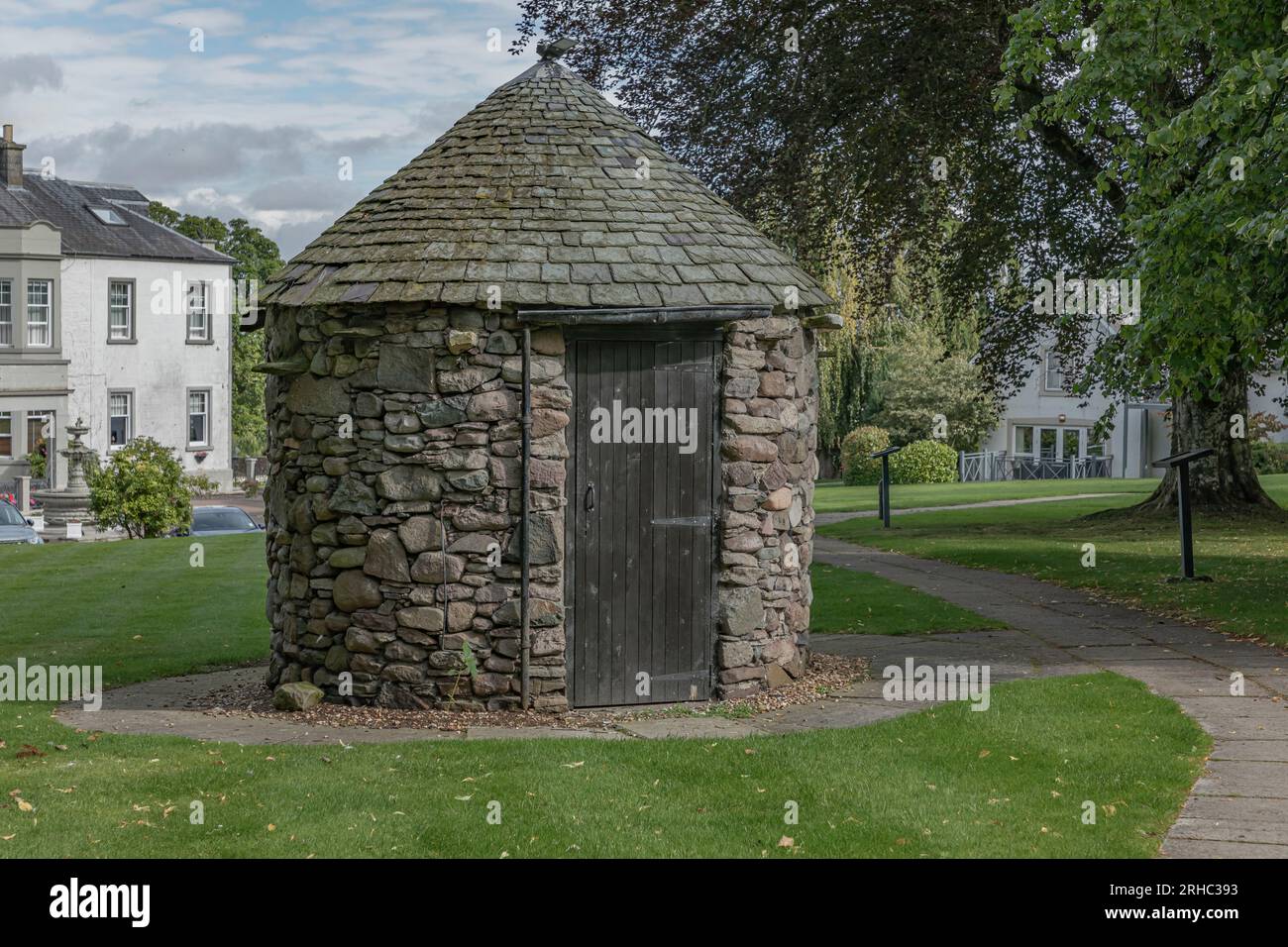 Round stone building with a tiled roof and a black painted door Stock Photo