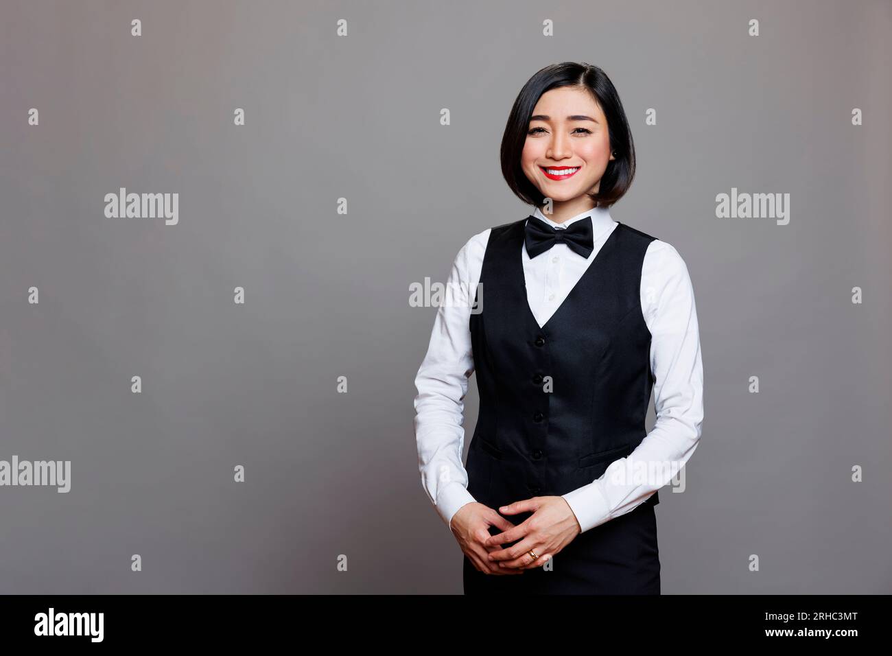 Smiling asian restaurant waitress wearing black and white uniform standing  and looking at camera. Cheerful young woman professional receptionist  posing for studio portrait Stock Photo - Alamy