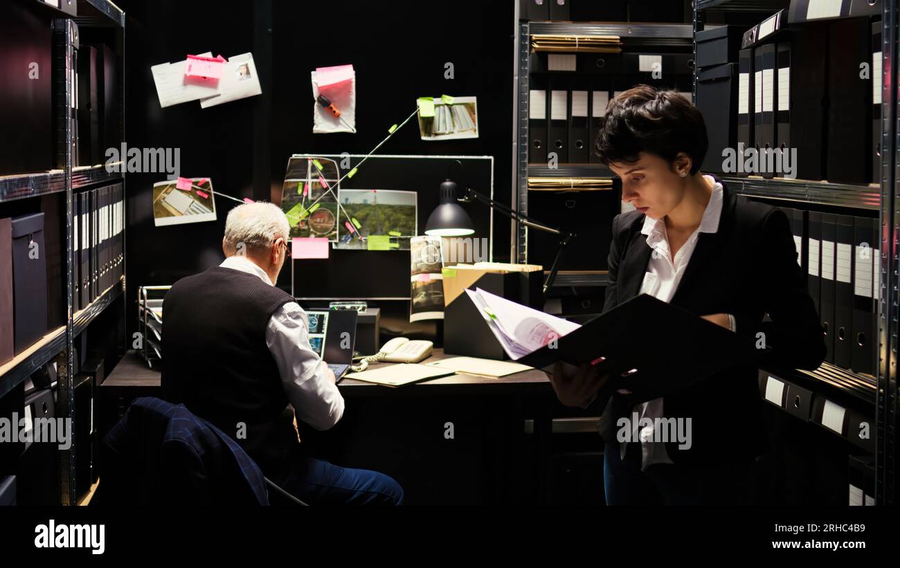 Partners searching for new case clues, invading criminal privacy and reviewing existing police database with illegal activity records. Inspector and agent work on solving crime, gather intelligence. Stock Photo