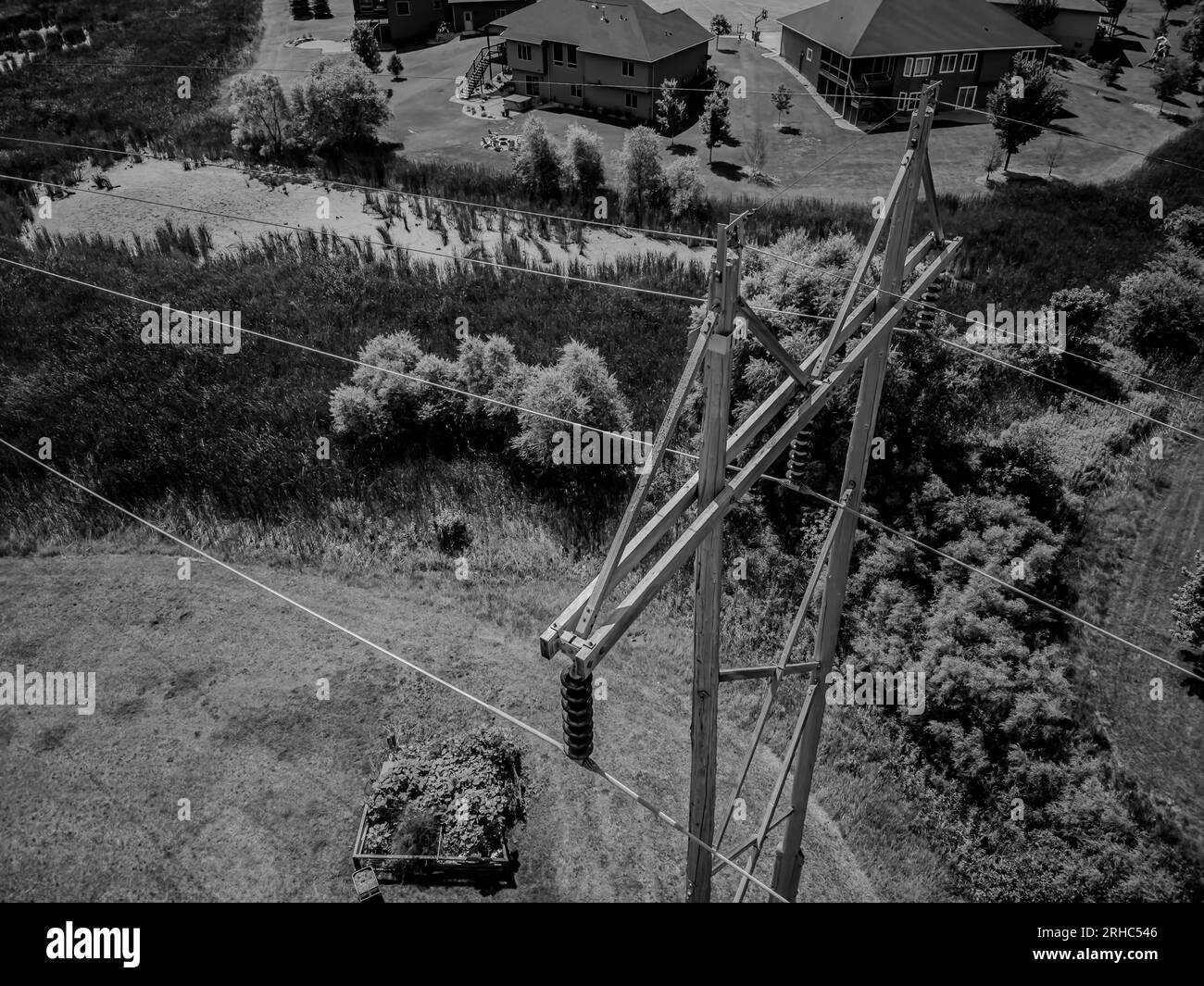 Drone aerial view of high voltage power lines through a residential suburb.  Stock Photo